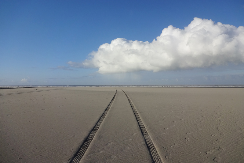 sporen in strand met witte wolk aan de einder